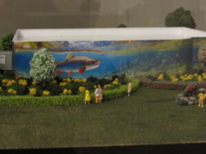 Building model with a salmon mural on the side, landscaping and figurines of visitors